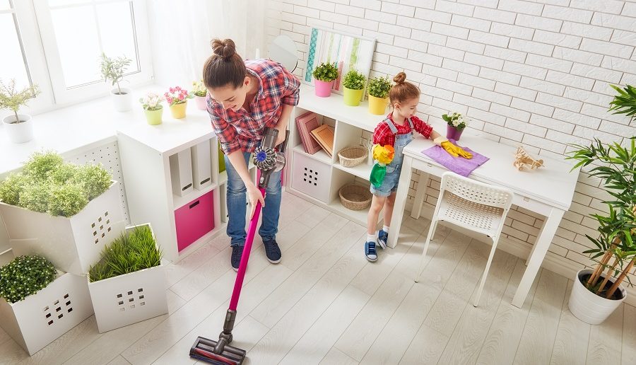 mother and daughter using a cordless vacuum cleaner to clean the kitchen floor