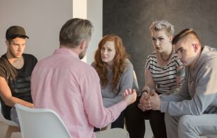 Addiction counselor talking to group of his teenage patients