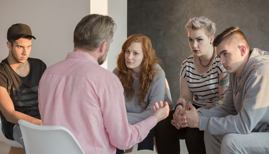 Addiction counselor talking to group of his teenage patients